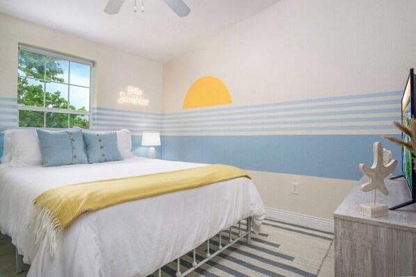 Un dormitorio con cama, mesita de noche, lámpara y una decoración con forma de estrella de mar.