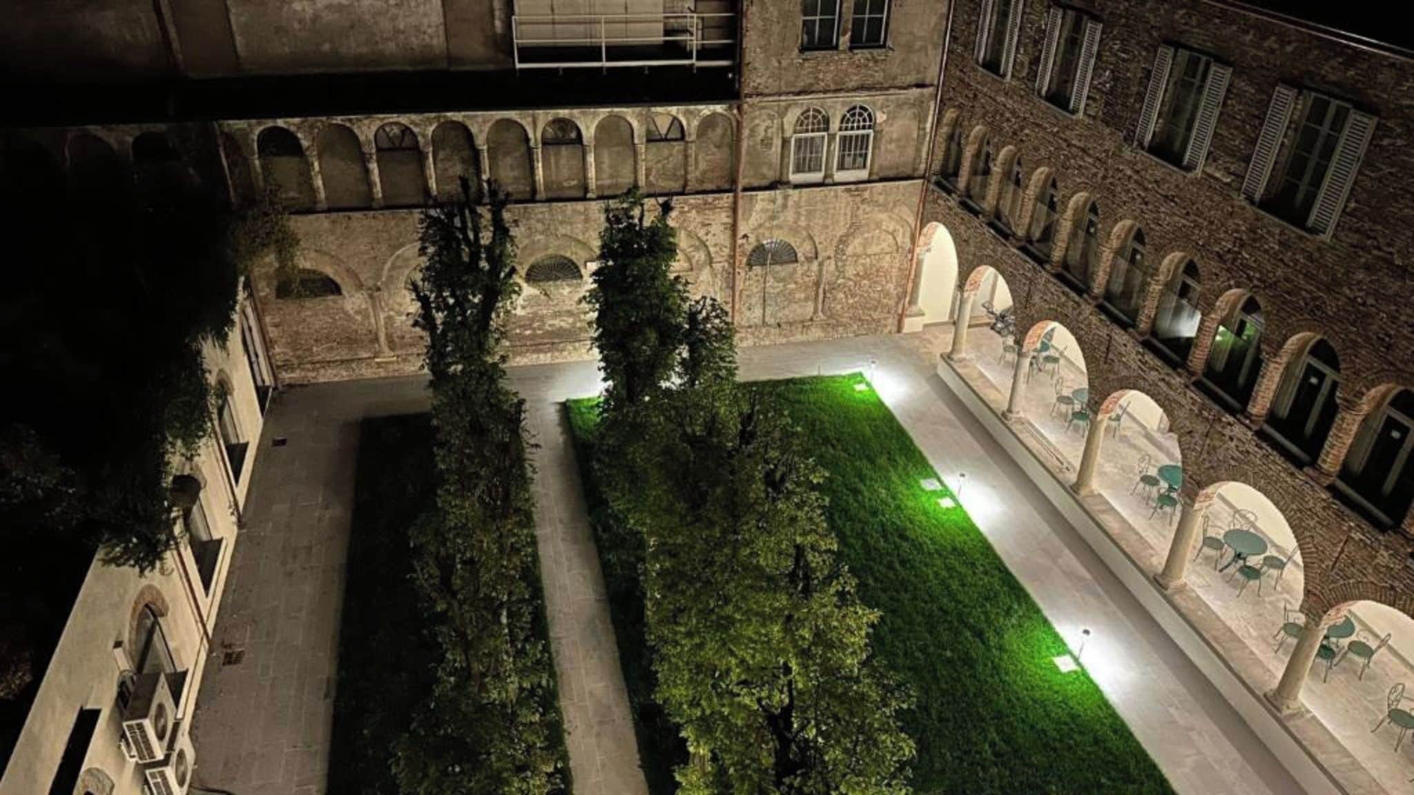 An outdoor courtyard with a pathway, greenery, and seating areas.