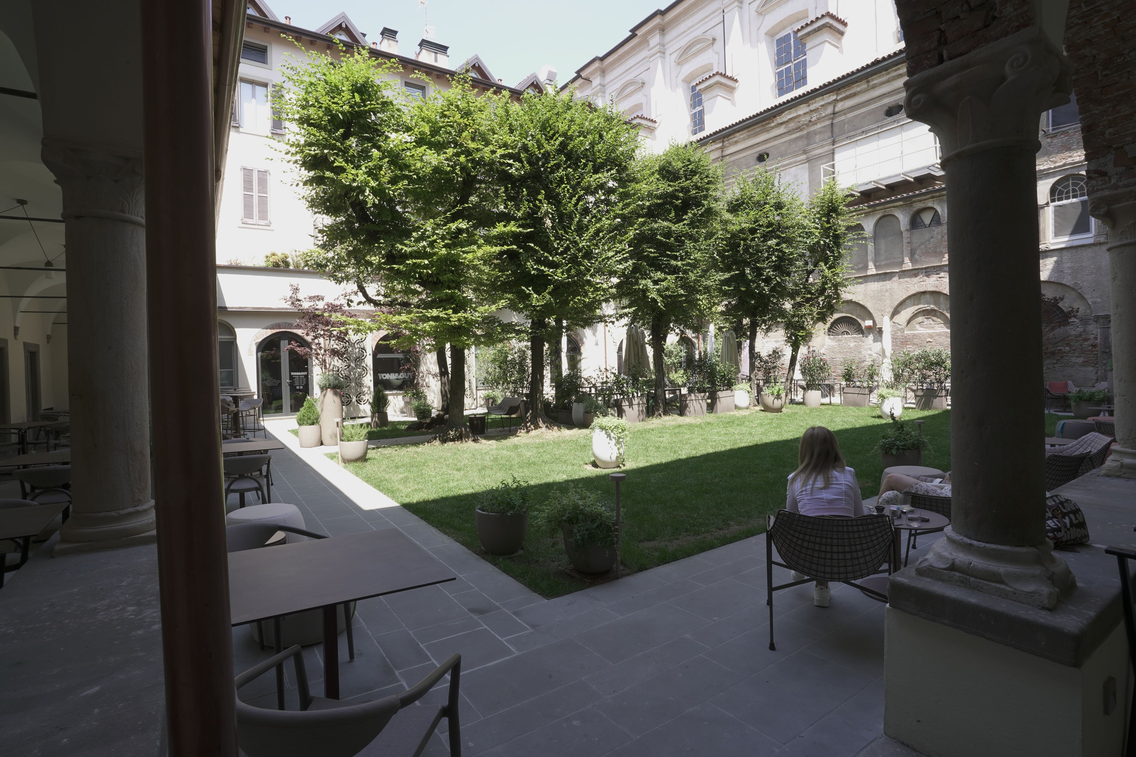 A courtyard with outdoor seating, a grassy area, and classical architecture.