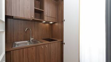 A compact kitchen with wooden cabinetry, a stainless steel sink, and under-cabinet lighting.