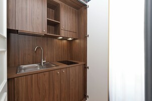 Una cucina compatta con mobili in legno, un lavello in acciaio inossidabile e illuminazione sotto i pensili.