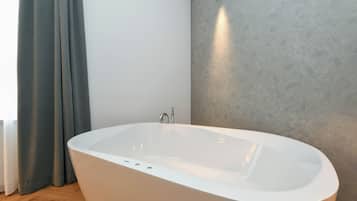 Une salle de bain moderne avec une baignoire sur pieds, une douche et un mur uni.