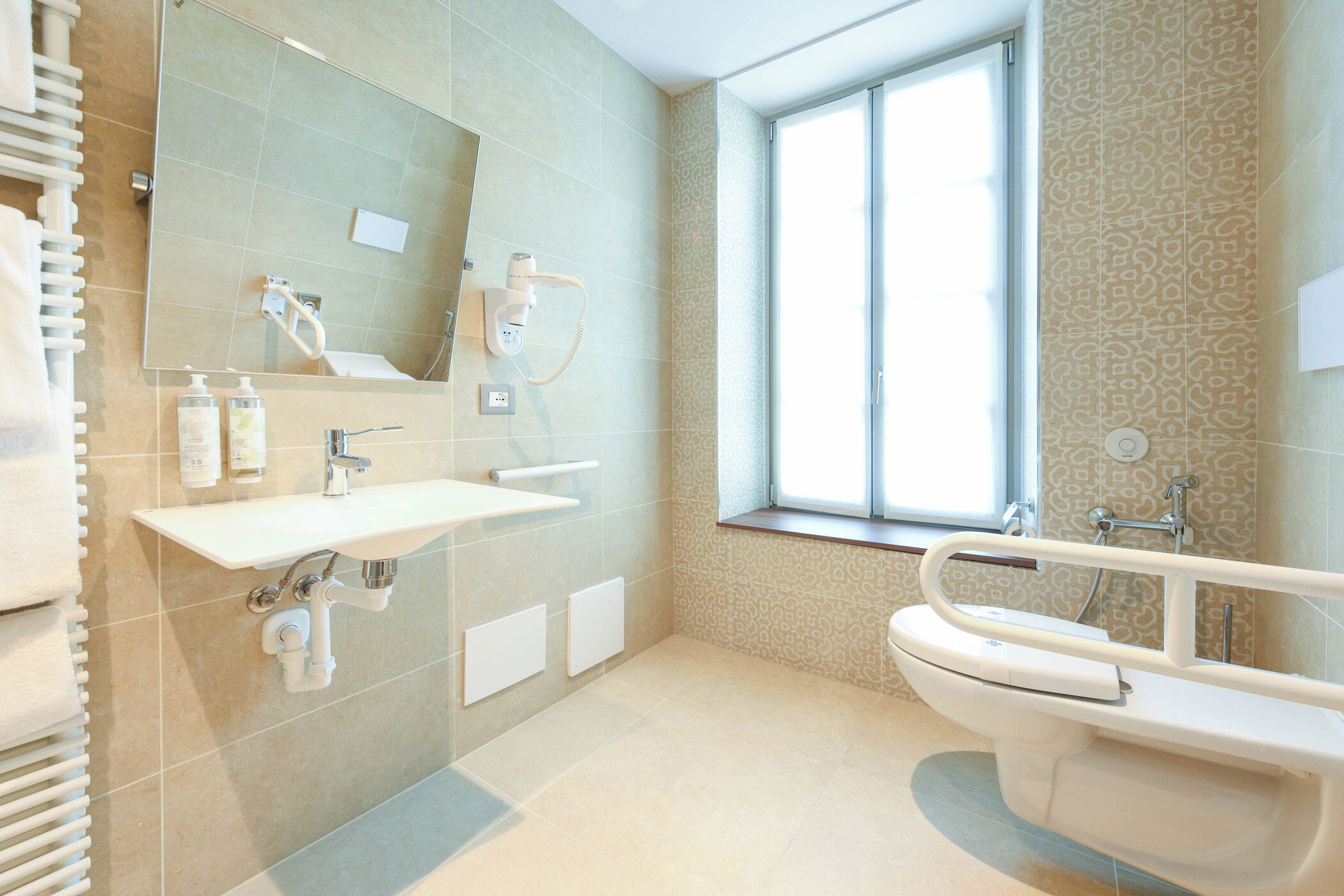 Ein modernes Badezimmer mit einem großen Spiegel, einem Waschbecken, einer Toilette und einem Fenster.
