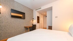 Ein Hotelzimmer mit einem großen Bett, einem Schreibtisch, einem Stuhl und einem Kleiderschrank.