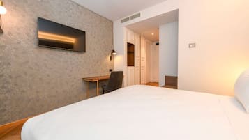 Una camera d'albergo con un letto grande, una scrivania, una sedia e un armadio.