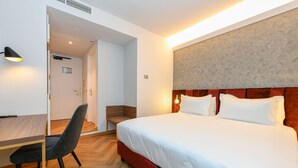 Ein Hotelzimmer mit Bett, Schreibtisch und Stuhl.