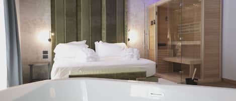 A modern hotel room with a large bed, a glass-enclosed wardrobe, and a small bedside table.