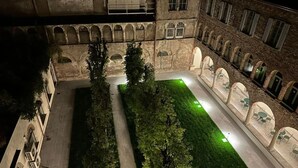 A courtyard with a central lawn, surrounded by buildings with arched windows and a stone facade. - Palazzo Santo Spirito (Bergamo)