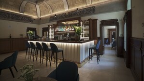 A bar area with a high ceiling and ornate ceiling design, bar stools, and a counter with various bottles and glasses. - Palazzo Santo Spirito (Bergamo)