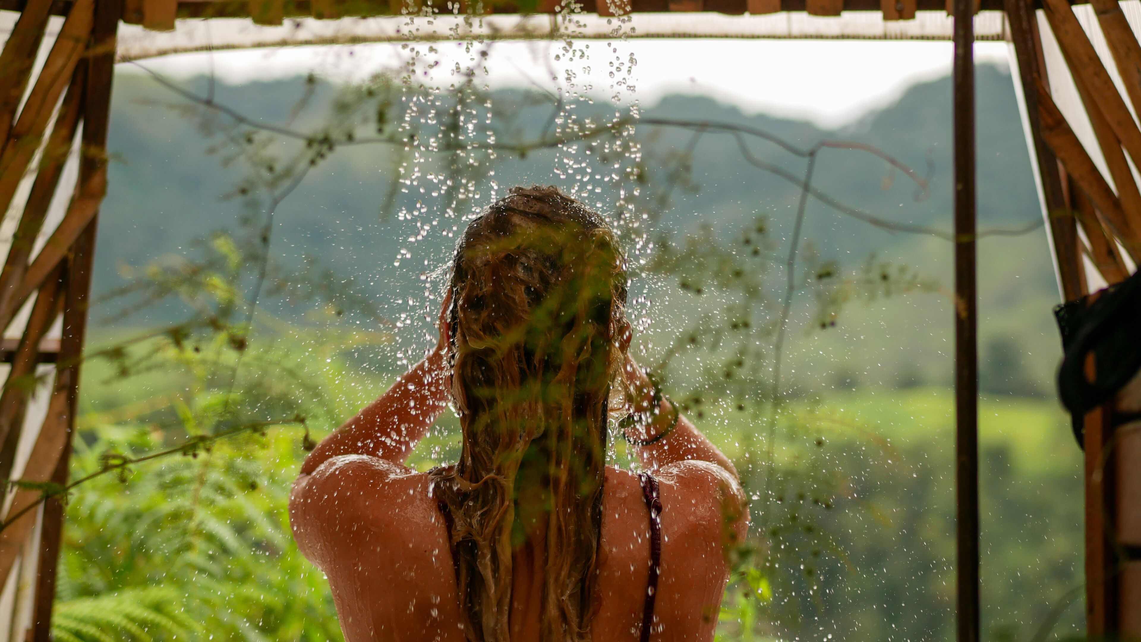 Una persona bajo una estructura de madera con gotas de agua visibles.
