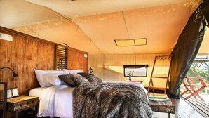 A tent-style bedroom with a bed, wooden headboard, and a small table with a lamp. - El Nido del Cóndor Ecolodge (Villamaria)