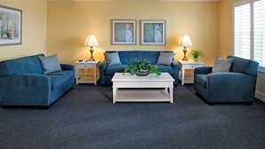 A living room with two blue sofas, a white coffee table, and two lamps. There are two framed pictures on the wall. - Three Bedroom, Luxury Condo, Hilton Head Island, SC 3348165 (Hilton Head Island)