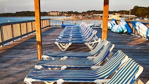 A wooden deck with striped lounge chairs facing a waterfront. - Three Bedroom, Luxury Condo, Hilton Head Island, SC 3348165 (Hilton Head Island)