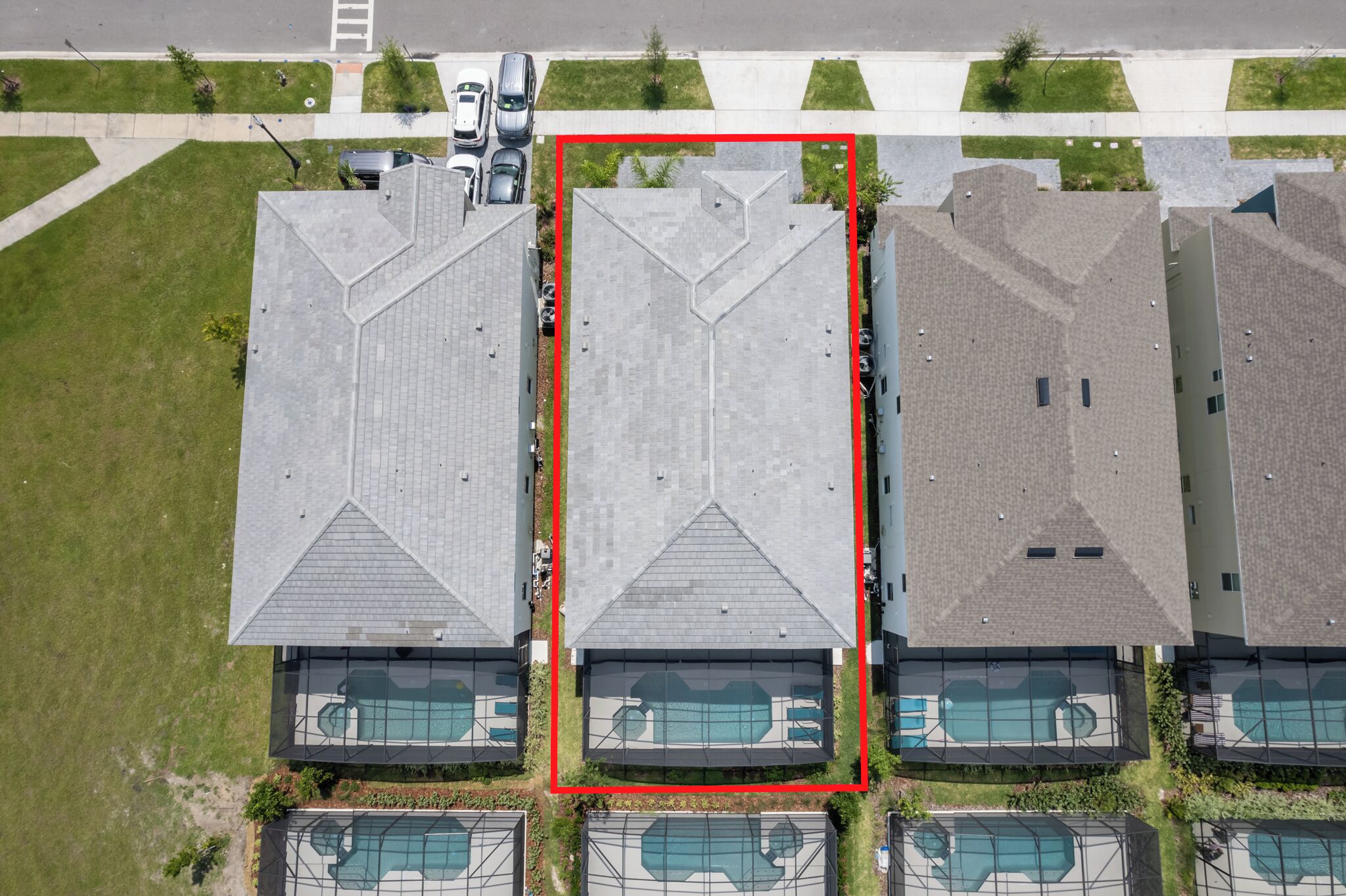 An aerial view of a residential area with multiple houses, each featuring a sloped roof and a swimming pool.