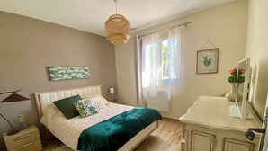 A bedroom with a bed, bedside table, lamp, and a window with curtains. - Quiet house with enclosed garden and terrace 5 minutes from the beach! (Travo)
