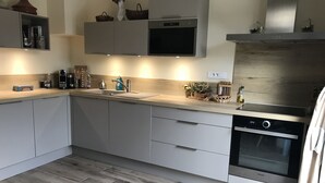 A modern kitchen with grey cabinets, a stainless steel oven, and a wooden floor. - Quiet house with enclosed garden and terrace 5 minutes from the beach! (Travo)