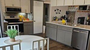 Een moderne keuken met een eethoek, met een plafondventilator, roestvrijstalen apparatuur en een accentmuur van baksteen.