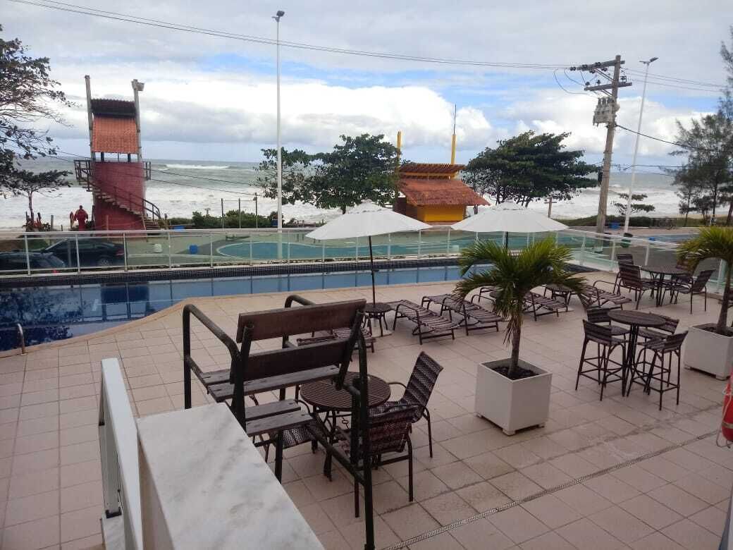 Zona junto a la piscina con mobiliario exterior, vista al océano y una torre de salvavidas.