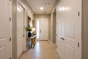 A hallway with white doors, a console table with a lamp, and a framed picture.