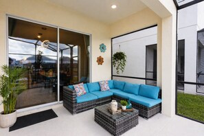 A modern outdoor seating area with a blue sofa, wicker tables, and potted plants.