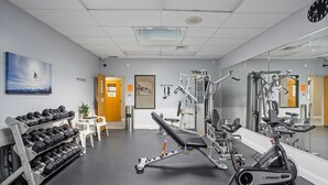 Een sportschool met trainingsapparatuur, een bank en een dumbbellsrek.
