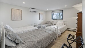 Een slaapkamer met drie bedden, een houten garderobe en een raam met uitzicht op bomen.