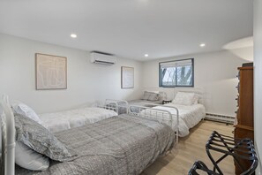 Un dormitorio con tres camas, un armario de madera y una ventana con vista a árboles.