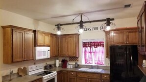 Una cocina con armarios de madera, microondas, estufa y refrigerador.