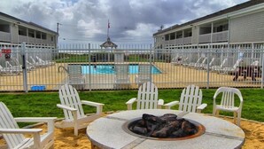 Ein Poolbereich mit Liegestühlen, einem Steinkamin und Blick auf ein Hotelgebäude.