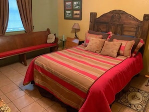 Une chambre à coucher avec un lit, un banc, une lampe et un tapis.