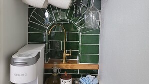 A kitchen with a Keurig coffee maker, a bottle of Pinot Noir, and a sugar container. - Historic Intimate Studio A (Haines City)