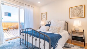Un dormitorio con cama, dos mesitas de noche, una ventana con cortinas y vistas al exterior.