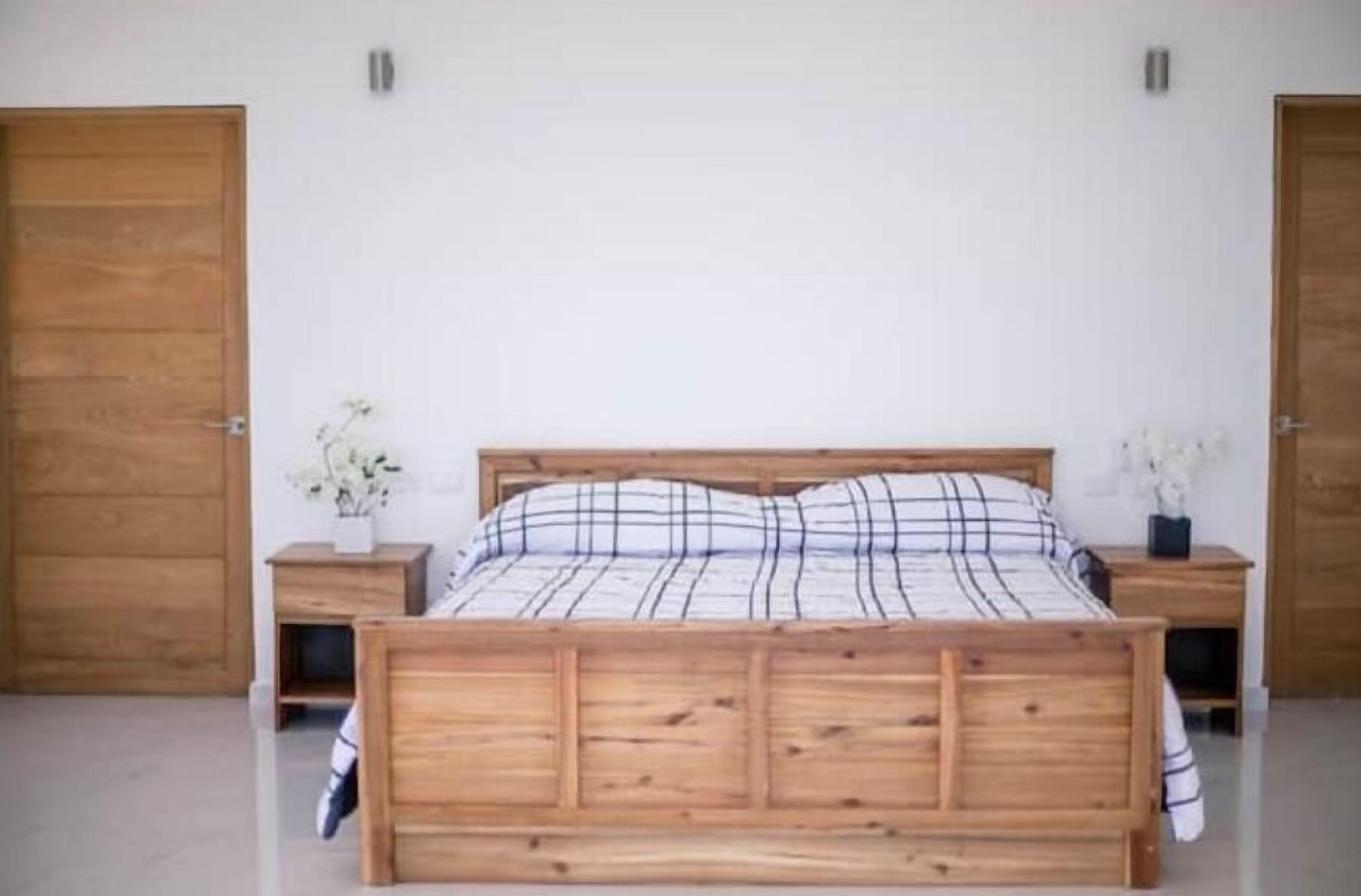 Een slaapkamer met een houten bed, twee nachtkastjes en witte muren.