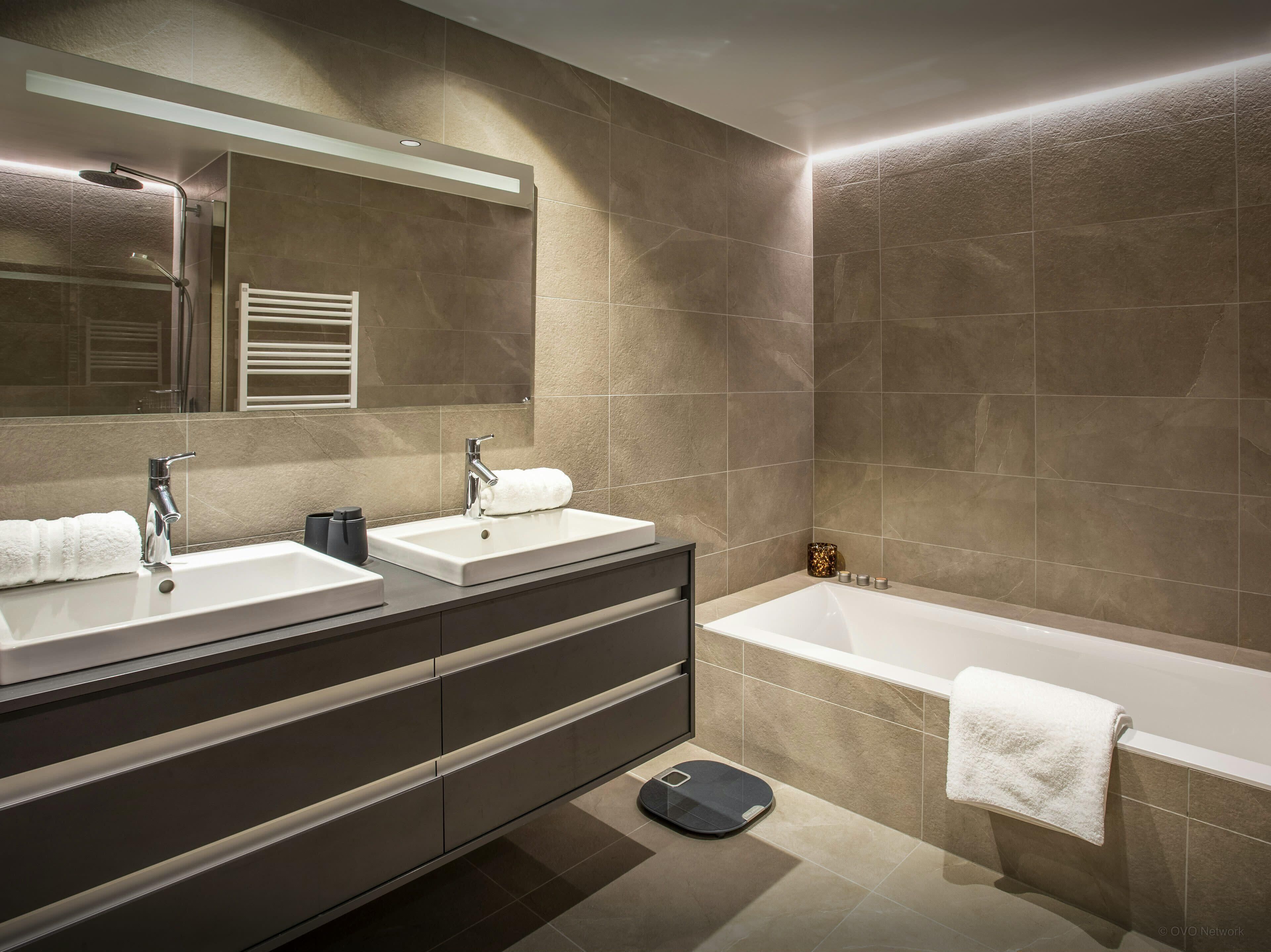 Un baño moderno con dos lavamanos, una bañera grande y una balanza.