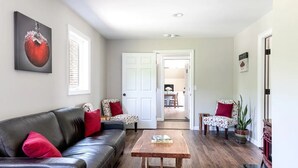 Un salon avec un canapé en cuir noir, une table basse en bois et une porte donnant sur un coin repas.