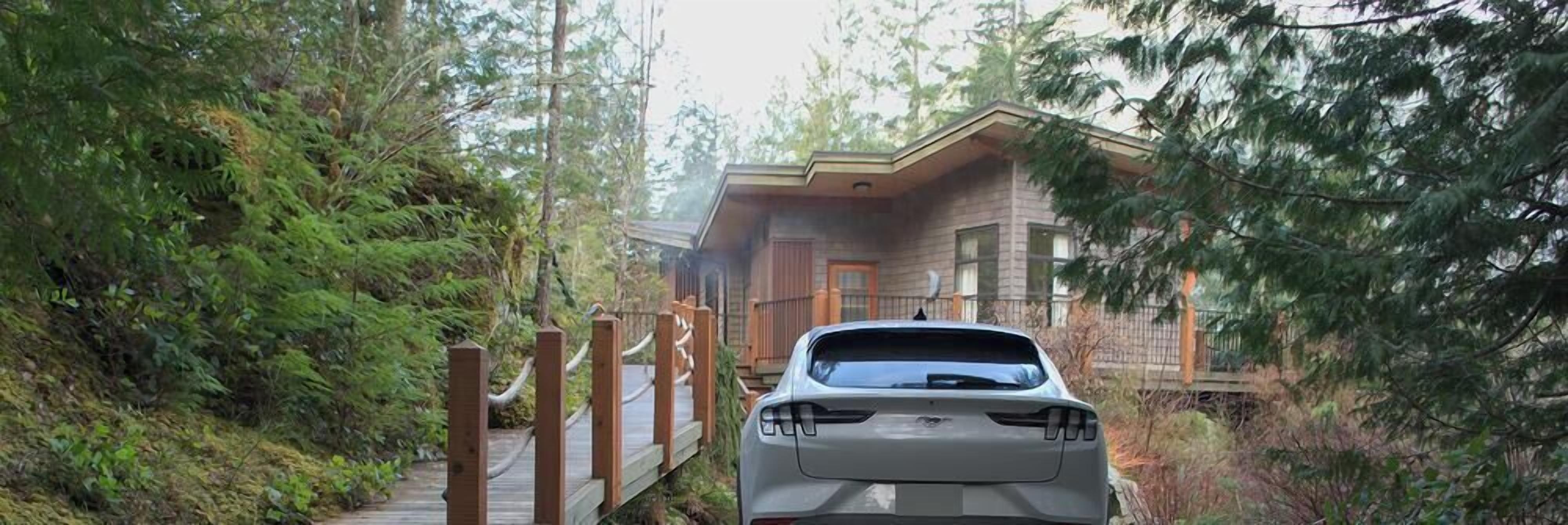 A vehicle parked in front of a cabin with a wooden deck leading to the entrance.
