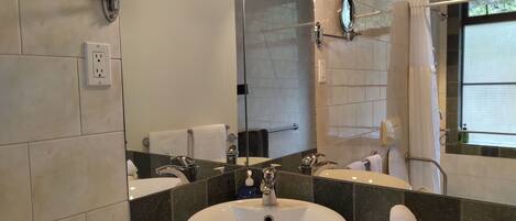 Een moderne badkamer met een grote spiegel, een witte wastafel en een douchehoek.