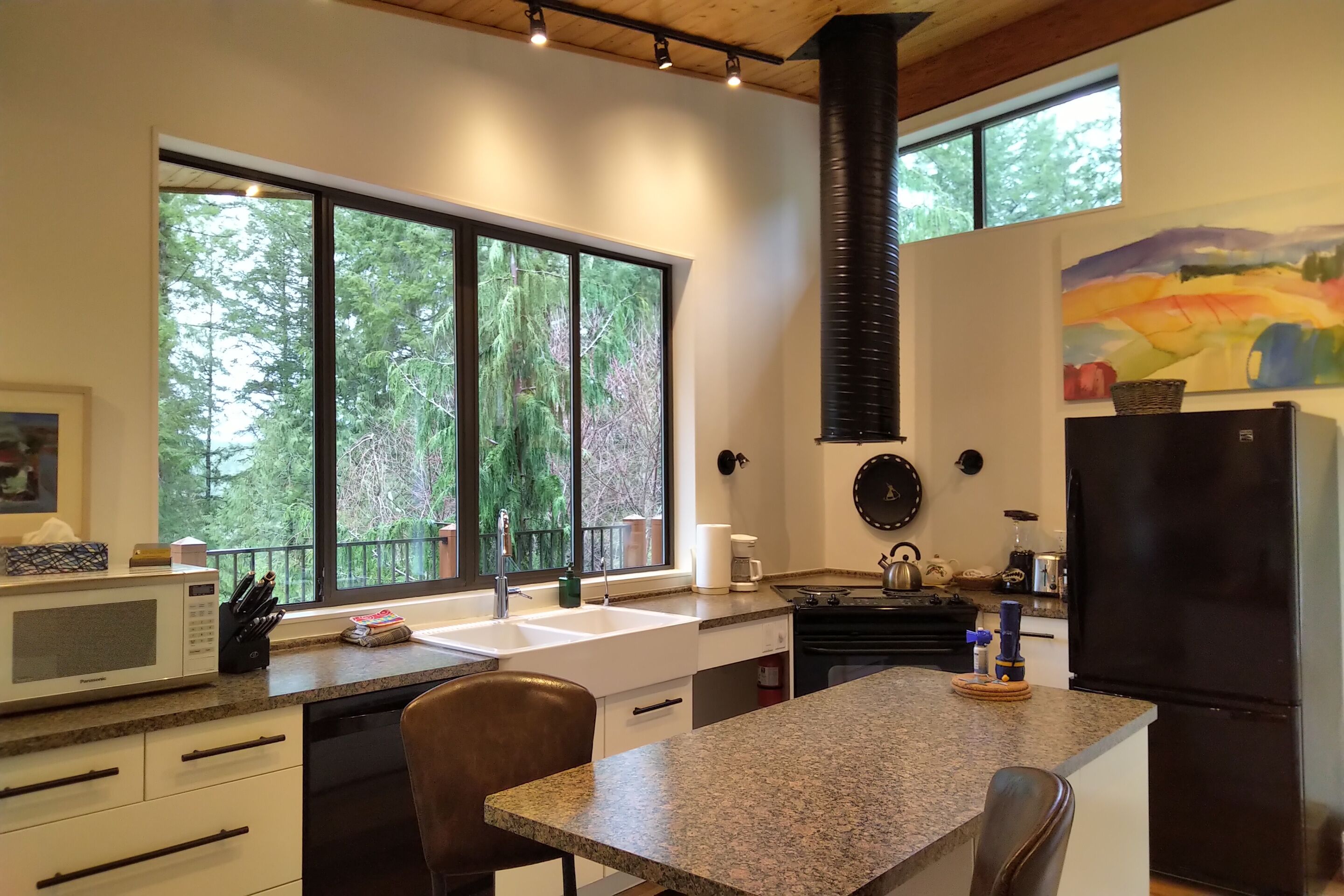 A modern kitchen with a large window, a stove, and a refrigerator.