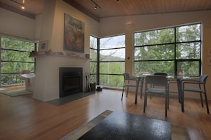 A spacious room with a fireplace, large windows, and a dining area. - Waterview Architectural Gem - Romantic Seclusion! (Madeira Park)