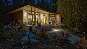 A modern house with a large wooden structure, a stone wall, and a pathway leading to the entrance. - Modern Forest Guest Suite - Accessible Seclusion! (Madeira Park)