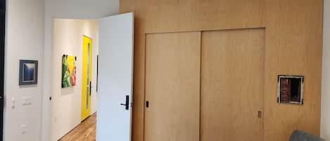 A room with a wooden floor, a white door, a grey chair, and a small window.