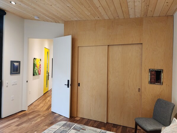 Ein Zimmer mit Holzboden, einem grauen Stuhl und einer weißen Tür.