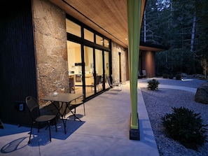 Un edificio moderno con fachada de piedra, amplias ventanas y un patio con mobiliario exterior.