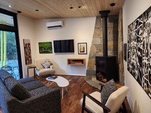 A modern living room with a fireplace, comfortable seating, a flat-screen TV, and artwork on the walls.