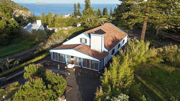 A coastal house with a large bay window, surrounded by dense greenery and a view of the sea. - Casa do Monte - Garden & Sea sight (Caloura)