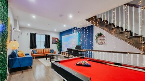 Ein modernes Wohnzimmer mit Billardtisch, einer Couch und einer Treppe.