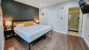 Ein Hotelzimmer mit Bett, Nachttischen, einer Wand mit Sternenmuster, einem Fernseher und einer Duschkabine.