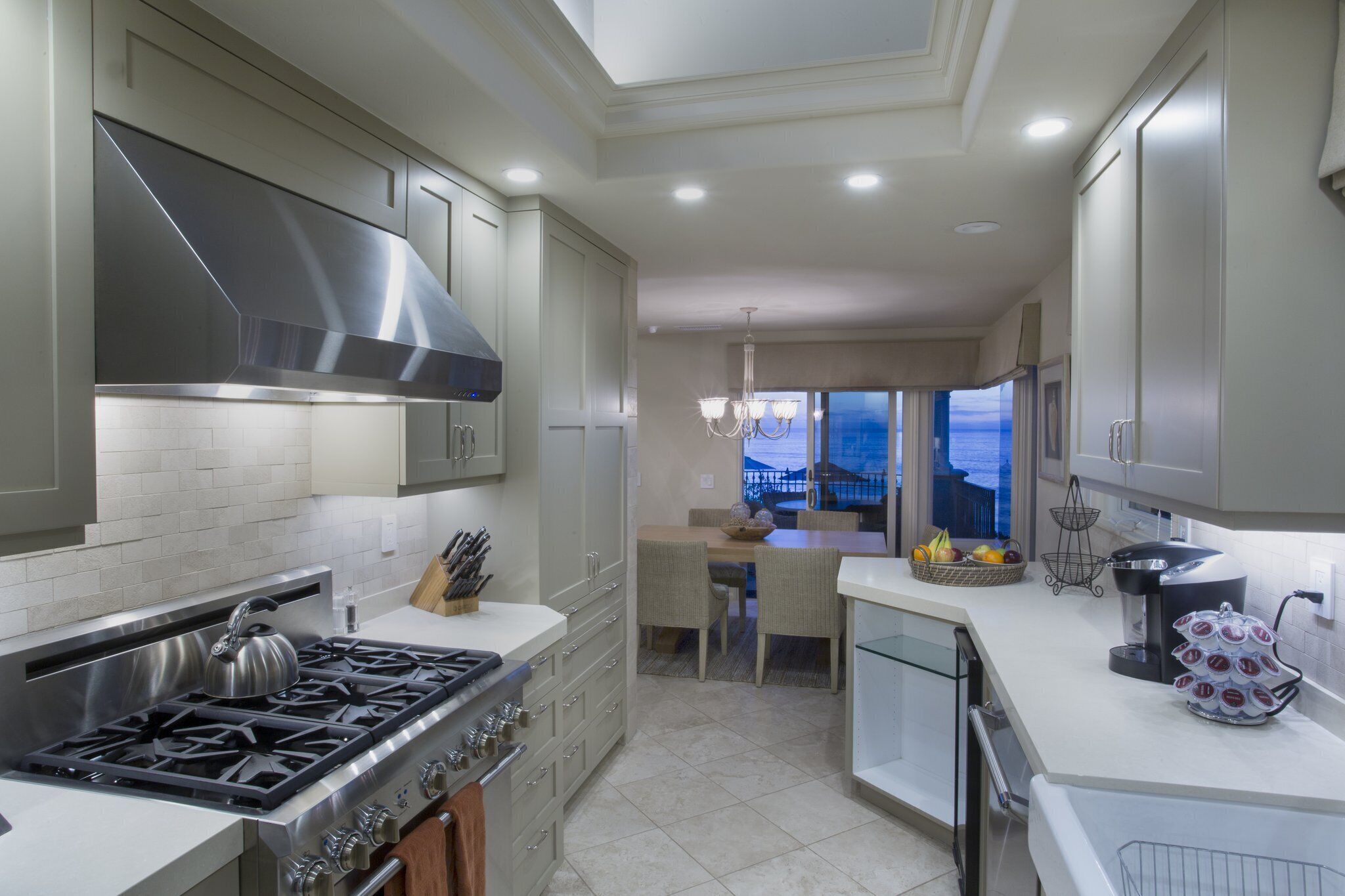 A modern kitchen with stainless steel appliances, a dining area with a view, and a large window.