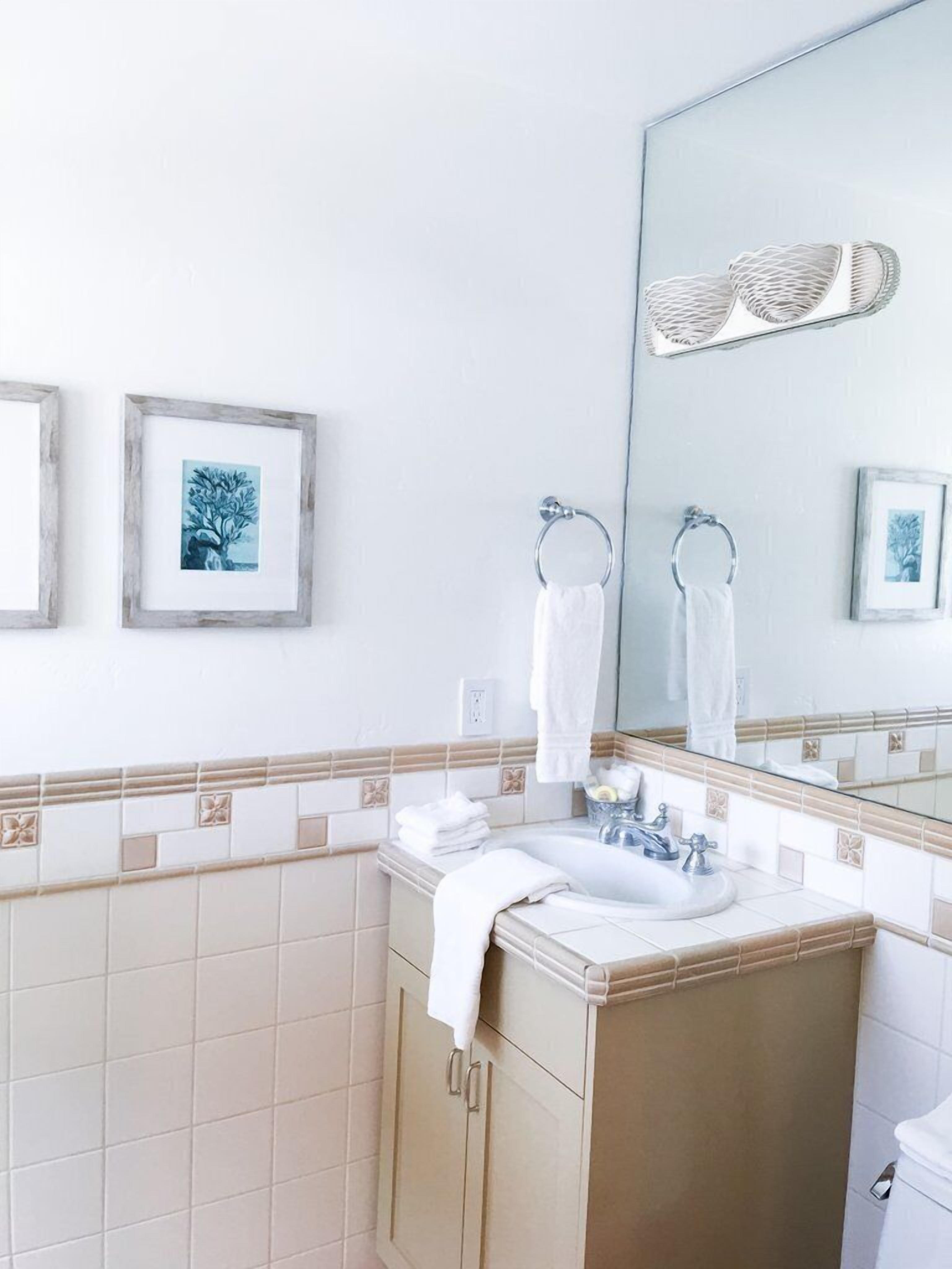 Une salle de bain avec un lavabo, un miroir et deux tableaux encadrés au mur.