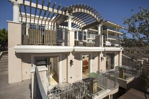Ein mehrstöckiges Gebäude mit Balkonen, einer überdachten Terrasse und einer Treppe.
